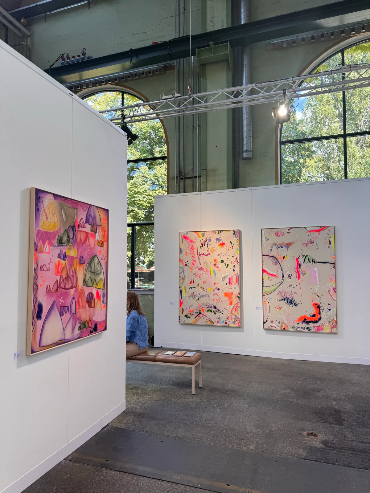 Contemporary paintings displayed on white walls in a spacious gallery.
